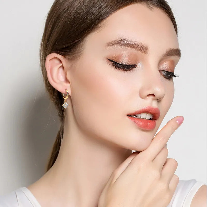 Small gold huggie hoops with dainty moissanite clover charm